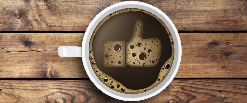 Coffee cup with foam shaped like a thumbs up indicating a social media profile