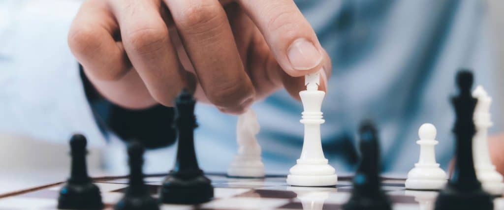 Hand moving white king chess piece on chessboard indicating decision making